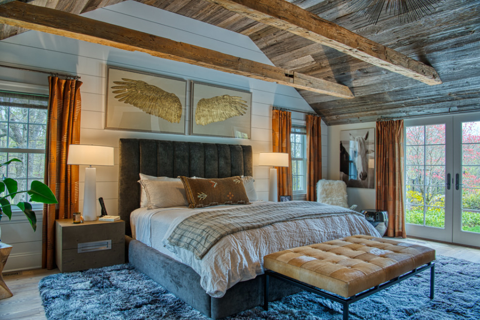 Inspiration for a large transitional master bedroom in New York with white walls, light hardwood floors, a two-sided fireplace, a stone fireplace surround, grey floor, exposed beam and planked wall panelling.