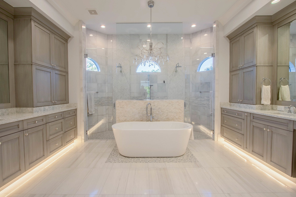 Huge transitional master white tile and porcelain tile porcelain tile and white floor freestanding bathtub photo with a two-piece toilet, an undermount sink, a hinged shower door, shaker cabinets, gray walls, quartz countertops and gray cabinets