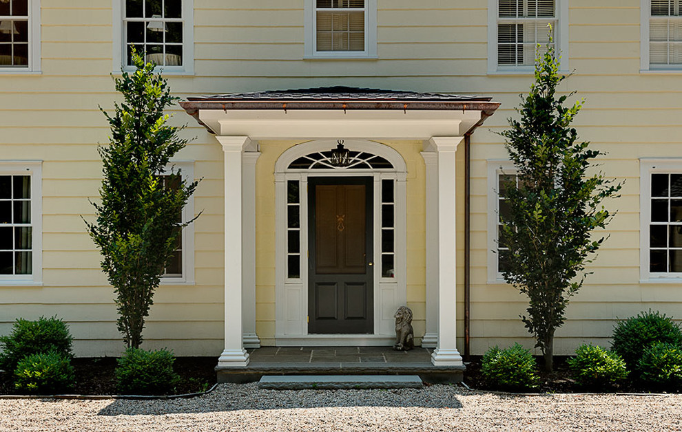 Traditional entryway in New York with a single front door and a black front door.
