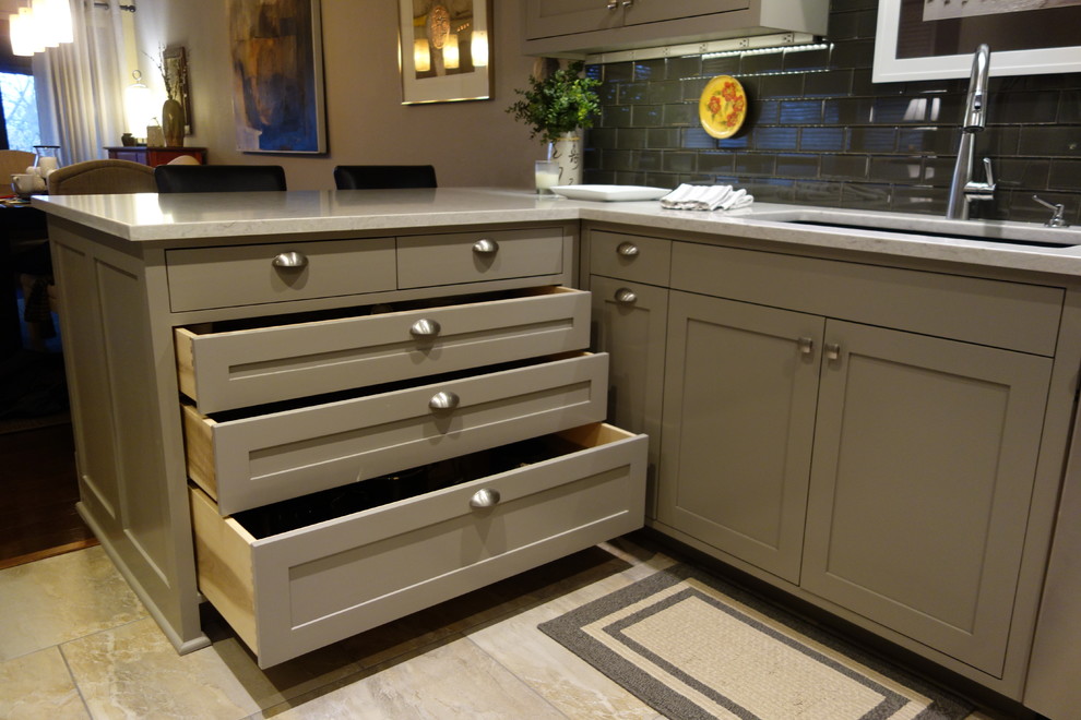 Small transitional u-shaped ceramic tile home design photo with an undermount sink, shaker cabinets, gray cabinets, quartz countertops, gray backsplash, glass tile backsplash, stainless steel appliances and a peninsula