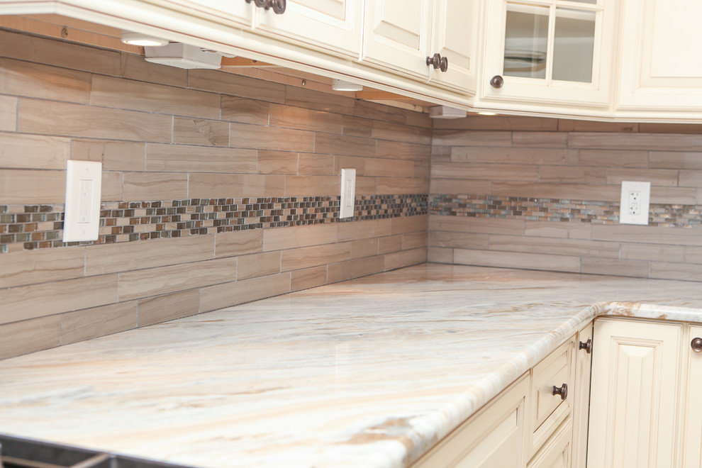 Large transitional u-shaped light wood floor eat-in kitchen photo in Newark with an undermount sink, raised-panel cabinets, distressed cabinets, granite countertops, brown backsplash, mosaic tile backsplash, stainless steel appliances and an island