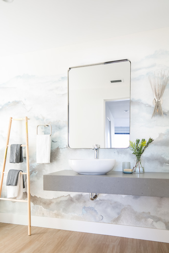 Inspiration for a mid-sized modern powder room in Los Angeles with open cabinets, a one-piece toilet, grey walls, ceramic floors, a vessel sink, solid surface benchtops and beige floor.