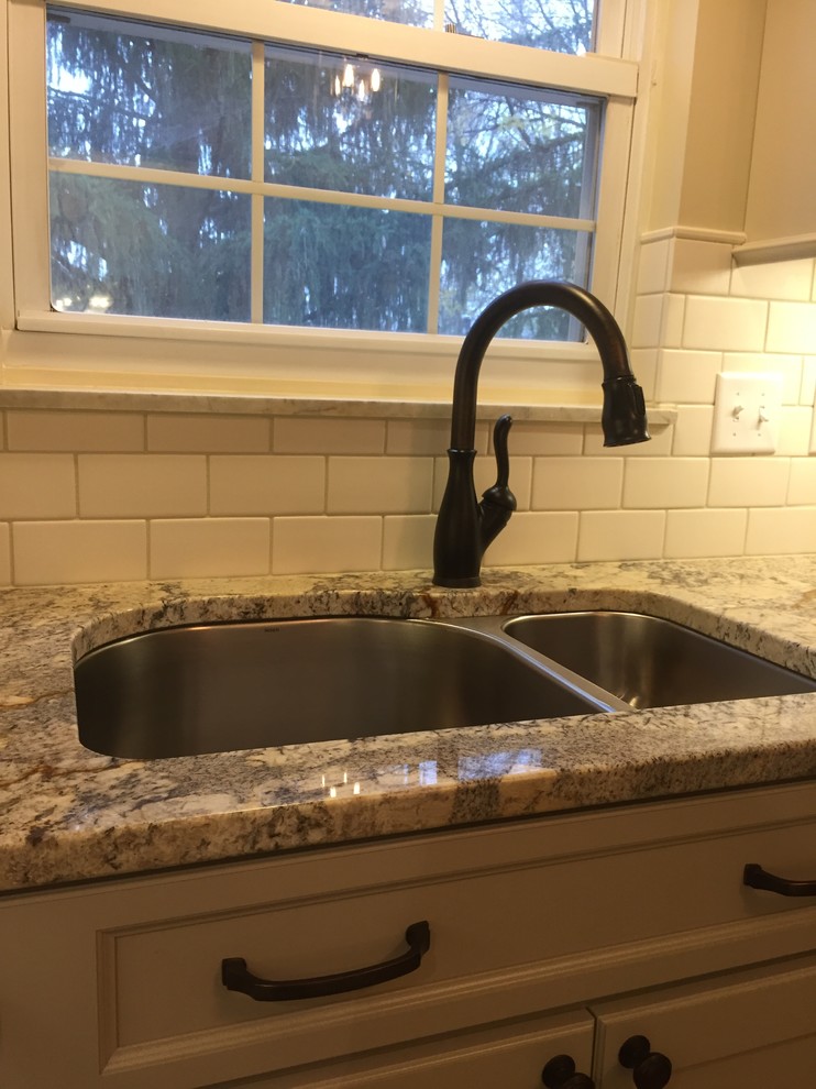 Inspiration for a rustic brown floor home design remodel in Cincinnati with a double-bowl sink, raised-panel cabinets, beige cabinets, granite countertops, white backsplash, terra-cotta backsplash and stainless steel appliances