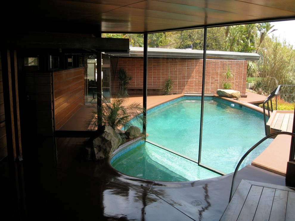 Photo of a mid-sized midcentury custom-shaped lap pool in Los Angeles with concrete slab.