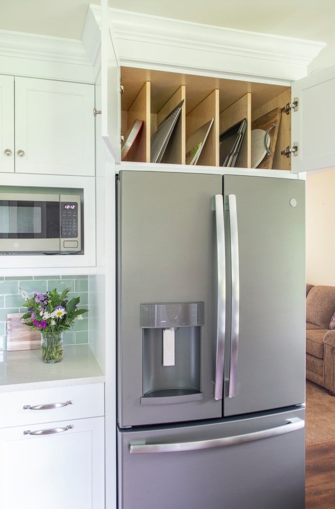 Transitional vinyl floor kitchen photo with an undermount sink, shaker cabinets, white cabinets, quartz countertops, green backsplash, glass tile backsplash, stainless steel appliances, no island and white countertops