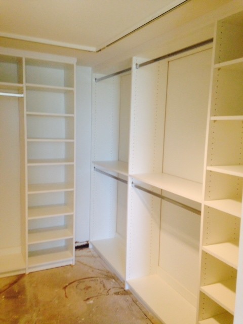 This is an example of a mid-sized modern gender-neutral walk-in wardrobe in Columbus with raised-panel cabinets, beige cabinets and dark hardwood floors.