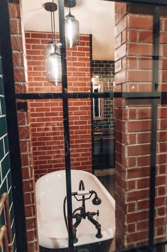 Cette image montre une salle de bain urbaine avec une baignoire indépendante, une douche d'angle, un sol en carrelage de céramique, un lavabo encastré, un sol gris, une cabine de douche à porte battante, un plan de toilette noir, meuble double vasque, un mur en parement de brique, un carrelage vert et un carrelage métro.