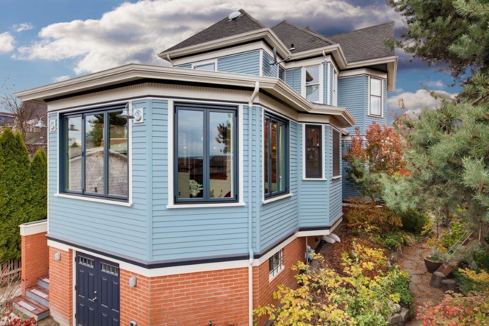 This is an example of a large traditional split-level blue house exterior in Seattle with mixed siding, a hip roof and a shingle roof.