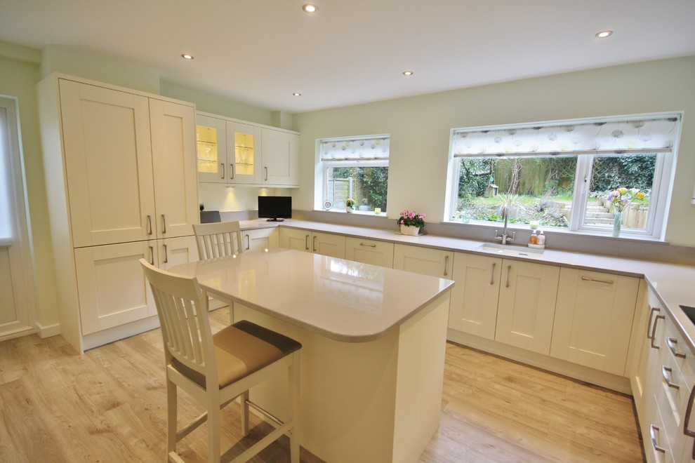 This is an example of a large contemporary separate kitchen in Essex with a drop-in sink, shaker cabinets, beige cabinets, quartzite benchtops, green splashback, glass sheet splashback, stainless steel appliances and with island.