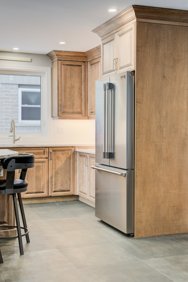 Inspiration for a mid-sized transitional l-shaped eat-in kitchen remodel in Toronto with an undermount sink, raised-panel cabinets, medium tone wood cabinets, quartz countertops, white backsplash, ceramic backsplash, stainless steel appliances, an island and white countertops