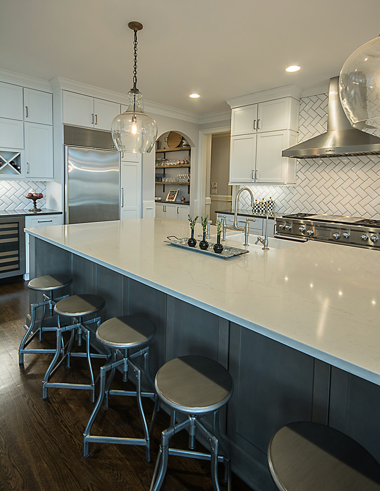 Large transitional l-shaped medium tone wood floor and brown floor open concept kitchen photo in Atlanta with a farmhouse sink, shaker cabinets, white cabinets, quartzite countertops, white backsplash, subway tile backsplash, stainless steel appliances and an island
