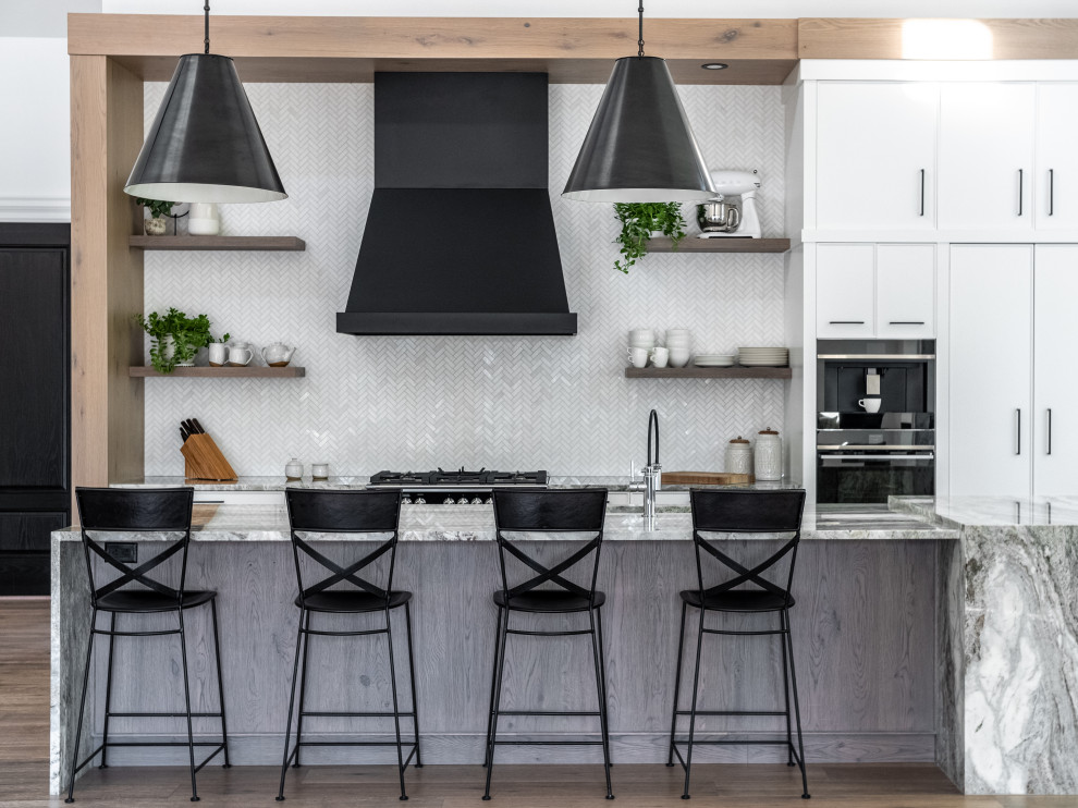 Inspiration for a transitional dark wood floor and brown floor kitchen remodel with flat-panel cabinets, white cabinets, white backsplash, stainless steel appliances, an island and multicolored countertops