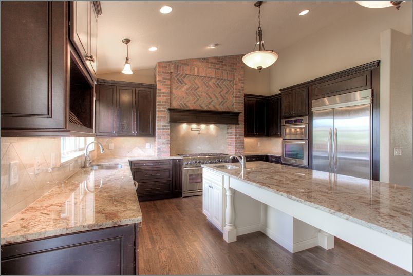 Design ideas for a large eclectic eat-in kitchen in Denver with an undermount sink, flat-panel cabinets, dark wood cabinets, granite benchtops, beige splashback, stone tile splashback, stainless steel appliances, dark hardwood floors and with island.