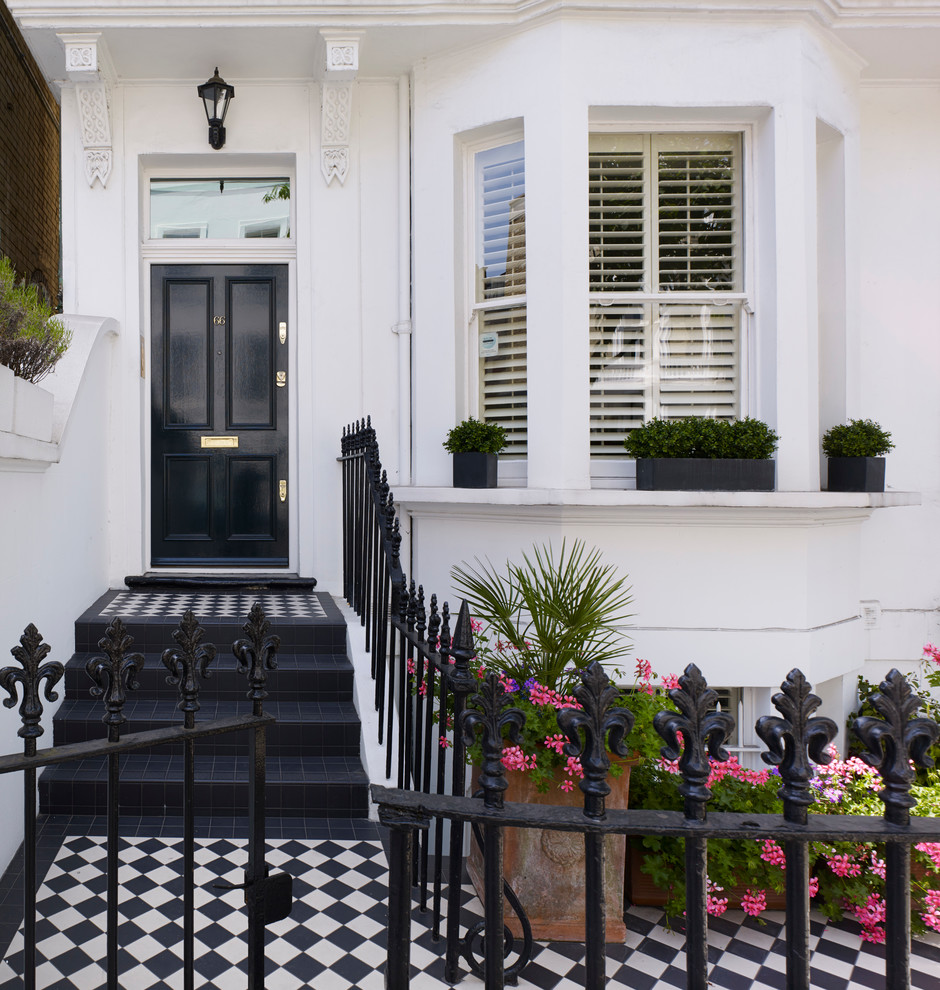 This is an example of a traditional front door in London with white walls, a single front door and a black front door.