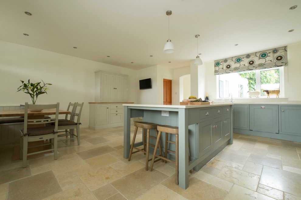 This is an example of an expansive traditional l-shaped eat-in kitchen in Cardiff with an undermount sink, shaker cabinets, green cabinets, quartzite benchtops, glass sheet splashback, coloured appliances, travertine floors and with island.