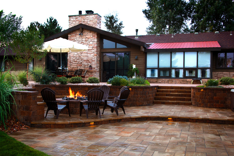 This is an example of a large modern partial sun backyard landscaping in Denver with a fire pit for spring.