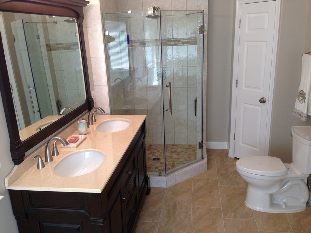 Mid-sized modern 3/4 bathroom in DC Metro with raised-panel cabinets, dark wood cabinets, a corner shower, a one-piece toilet, beige tile, ceramic tile, beige walls, ceramic floors, an undermount sink and tile benchtops.