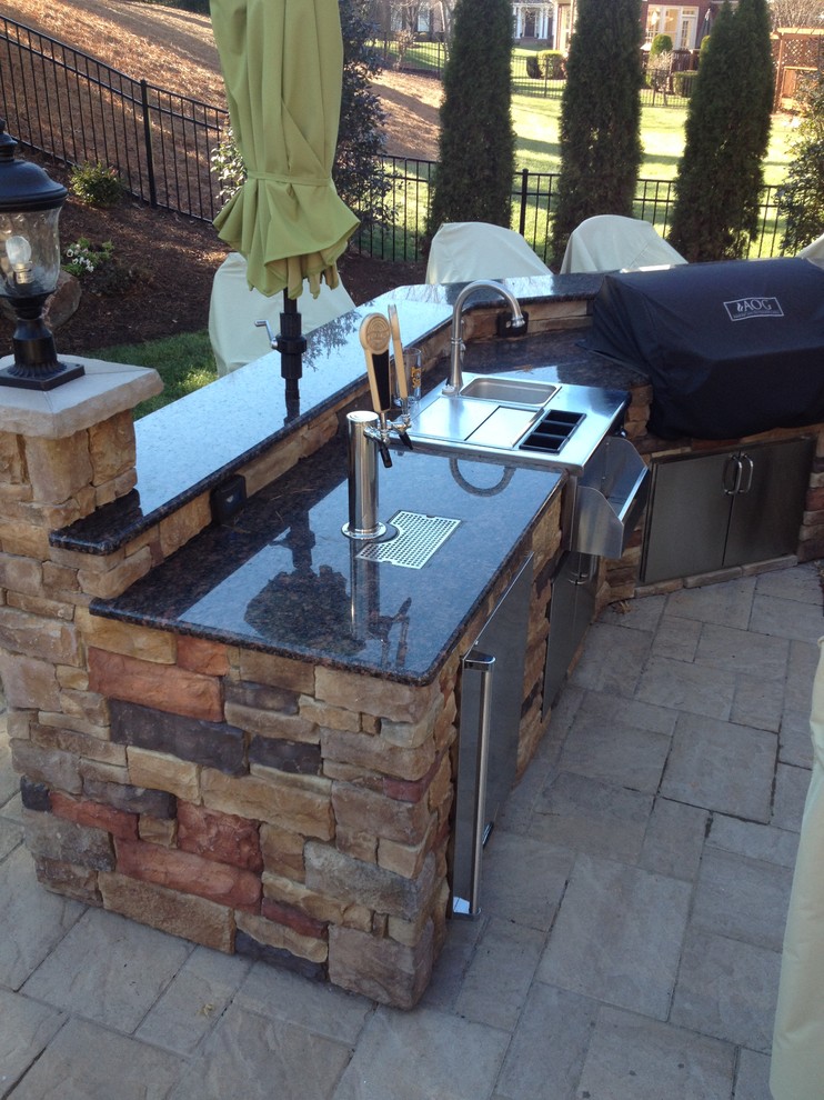 Large modern backyard patio in Charlotte with an outdoor kitchen and no cover.