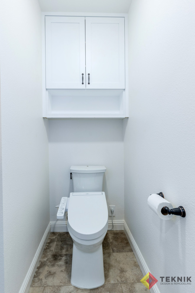 Photo of a large traditional cloakroom in San Diego with shaker cabinets, white cabinets, a bidet, beige tiles, ceramic tiles, ceramic flooring, a submerged sink, engineered stone worktops, grey floors, beige worktops, a built in vanity unit and wainscoting.