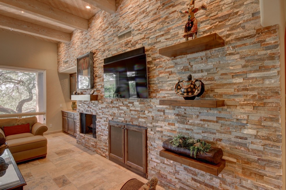 This is an example of a large traditional open concept living room in Phoenix with beige walls, limestone floors, a standard fireplace, a stone fireplace surround, a wall-mounted tv and beige floor.
