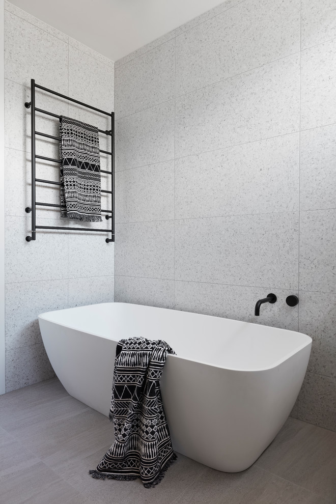 Photo of a mid-sized beach style master bathroom in Melbourne with recessed-panel cabinets, light wood cabinets, a freestanding tub, an open shower, gray tile, stone tile, a vessel sink, concrete benchtops, grey floor, a hinged shower door and white benchtops.