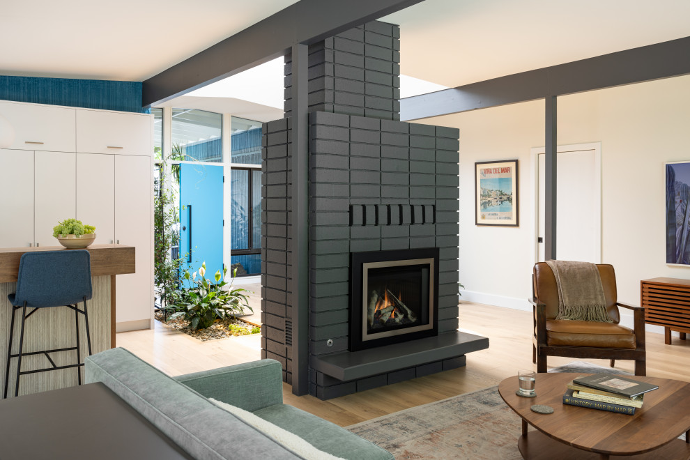 サクラメントにある高級な中くらいなミッドセンチュリースタイルのおしゃれなLDK (淡色無垢フローリング、両方向型暖炉、レンガの暖炉まわり、テレビなし、ベージュの床、表し梁、白い壁) の写真