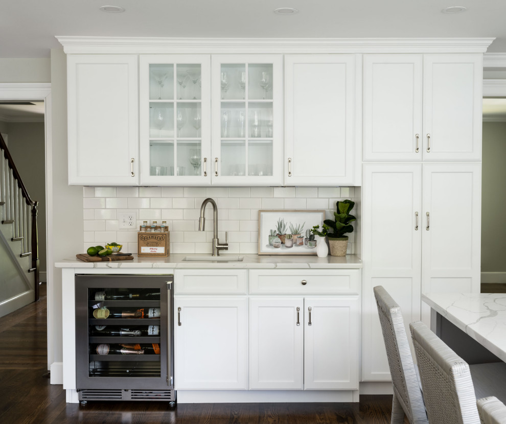Bild på ett vintage vit vitt kök, med en undermonterad diskho, skåp i shakerstil, vita skåp, bänkskiva i kvarts, vitt stänkskydd, stänkskydd i keramik, rostfria vitvaror, mellanmörkt trägolv, en köksö och brunt golv