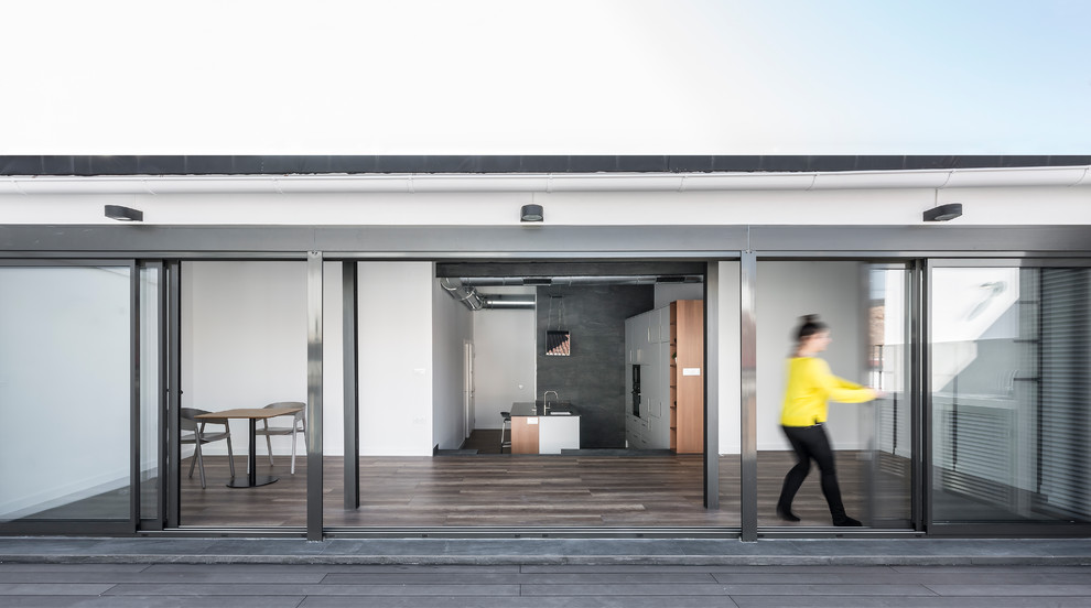 Imagen de sala de estar abierta industrial con paredes blancas y suelo laminado