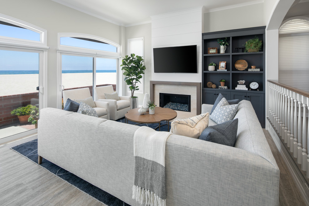 Beach style family room in Orange County with grey walls, a ribbon fireplace, a wall-mounted tv and brown floor.