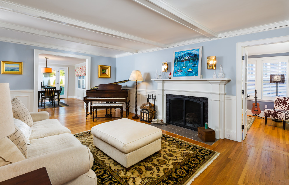 Photo of a mid-sized traditional enclosed living room in Boston with a music area, blue walls, medium hardwood floors, a standard fireplace, a wood fireplace surround, exposed beam and decorative wall panelling.