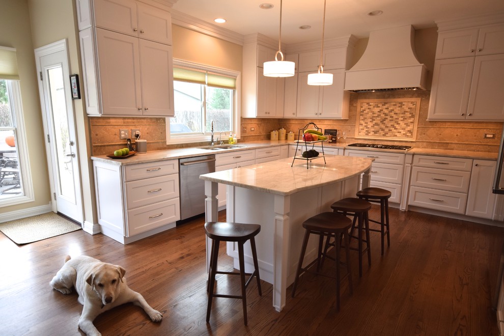 Inspiration for a large transitional u-shaped dark wood floor eat-in kitchen remodel in Chicago with an undermount sink, recessed-panel cabinets, white cabinets, marble countertops, beige backsplash, stone tile backsplash, stainless steel appliances and an island