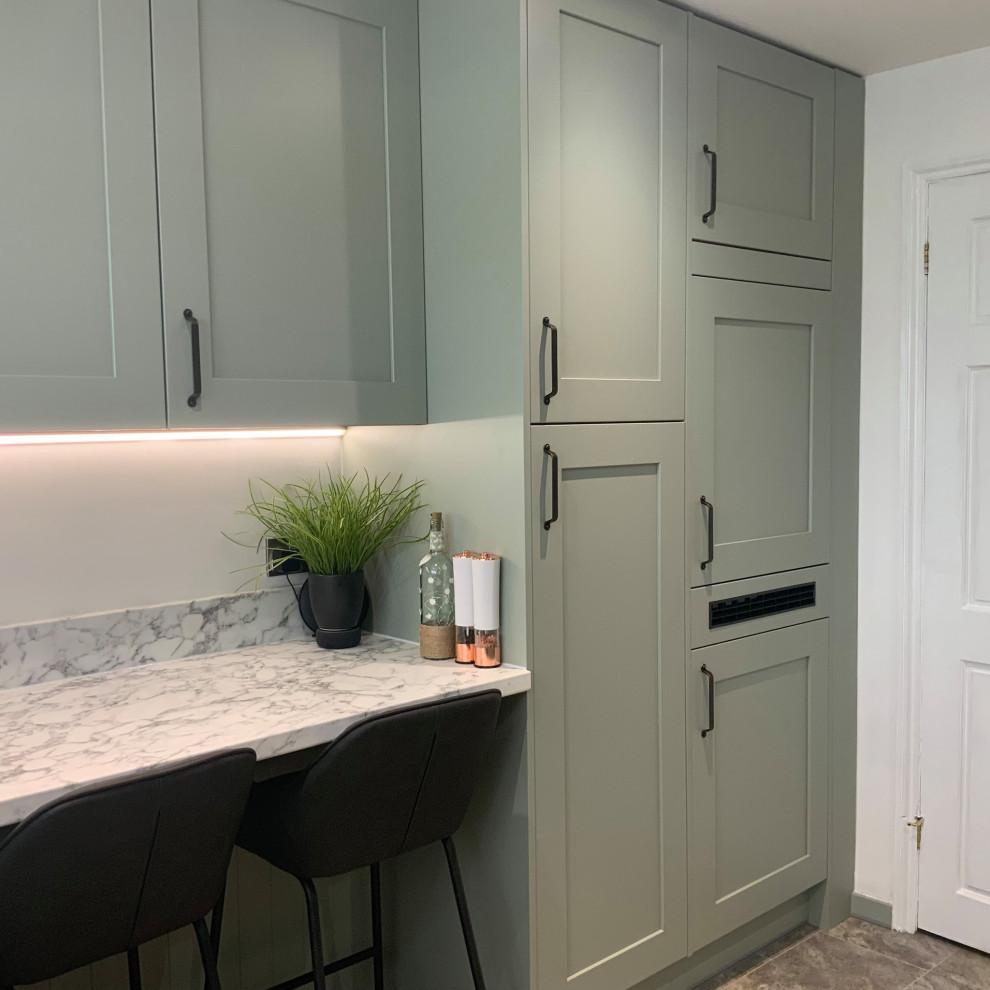 This is an example of a medium sized contemporary u-shaped enclosed kitchen in Buckinghamshire with shaker cabinets, green cabinets, laminate countertops, white splashback, glass sheet splashback, integrated appliances, a breakfast bar, grey floors and white worktops.