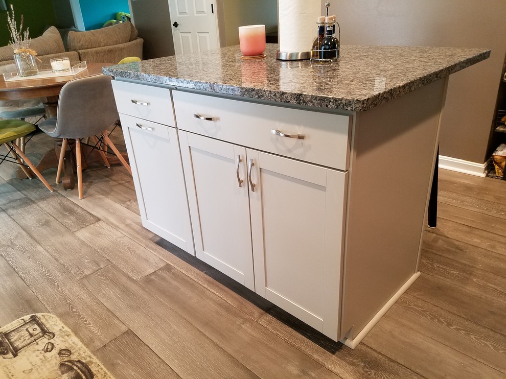 Mid-sized transitional l-shaped medium tone wood floor and gray floor eat-in kitchen photo with an undermount sink, shaker cabinets, white cabinets, granite countertops, multicolored backsplash, ceramic backsplash, colored appliances, an island and multicolored countertops