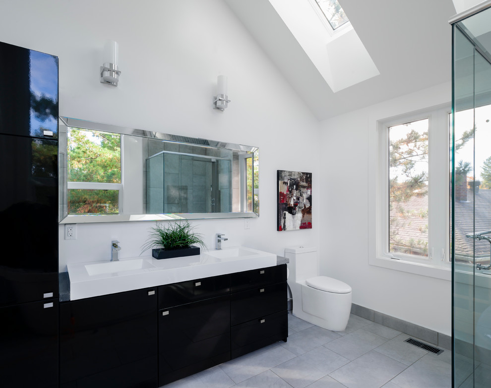 Large transitional master bathroom in Ottawa with flat-panel cabinets, black cabinets, a freestanding tub, a corner shower, a one-piece toilet, gray tile, porcelain tile, white walls, ceramic floors, an integrated sink and concrete benchtops.