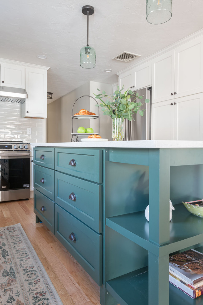 Example of a large transitional galley light wood floor and brown floor eat-in kitchen design in Boston with an undermount sink, shaker cabinets, white cabinets, quartz countertops, beige backsplash, ceramic backsplash, stainless steel appliances, an island and white countertops