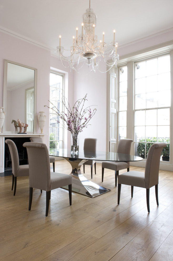 Large contemporary dining room in London with pink walls, light hardwood floors, a standard fireplace and a plaster fireplace surround.