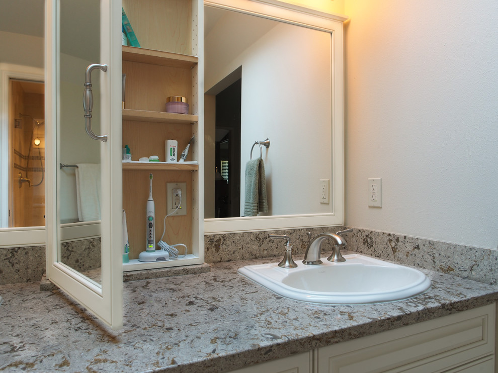 Photo of a large traditional master bathroom in Seattle with a drop-in sink, raised-panel cabinets, white cabinets, engineered quartz benchtops, a drop-in tub, an alcove shower, a two-piece toilet, beige tile, porcelain tile, white walls, porcelain floors, beige floor, a sliding shower screen, multi-coloured benchtops, a double vanity, a built-in vanity and recessed.