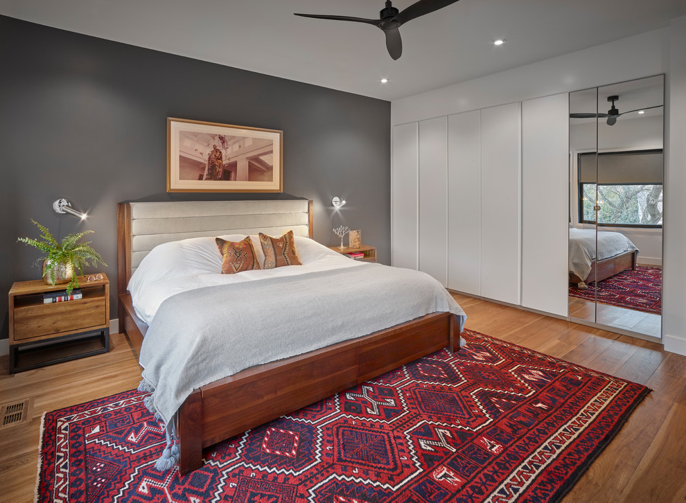 Midcentury master bedroom in Edmonton with grey walls, medium hardwood floors and no fireplace.