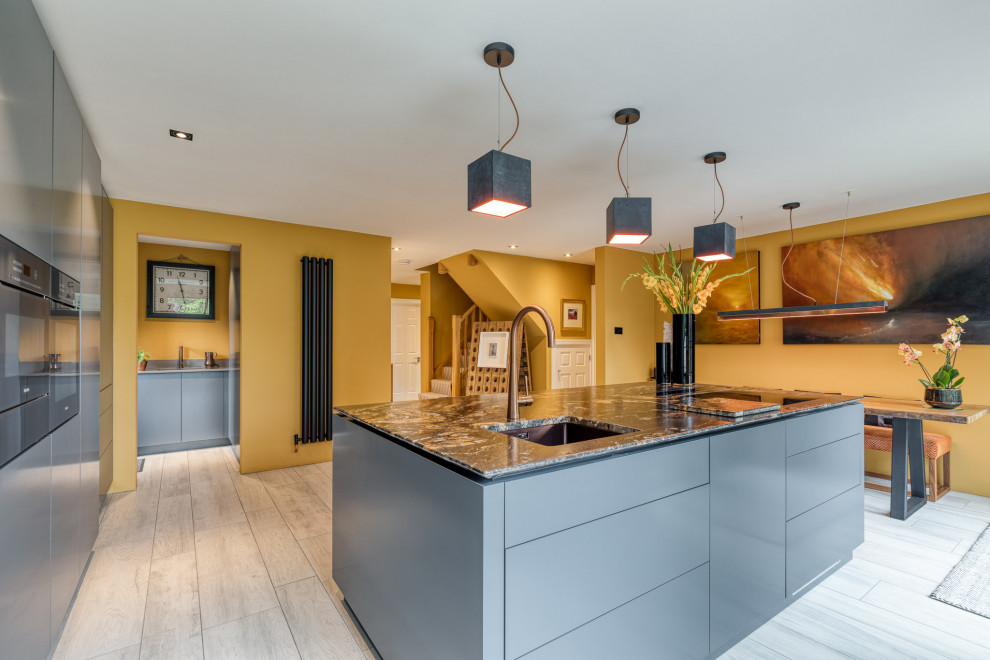 Photo of a large contemporary u-shaped eat-in kitchen in Hertfordshire with an integrated sink, flat-panel cabinets, grey cabinets, quartzite benchtops, panelled appliances, with island and black benchtop.