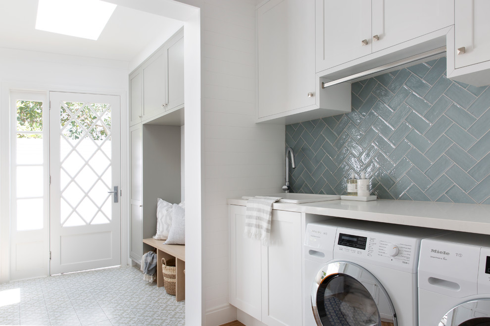 Photo of a beach style utility room in Gold Coast - Tweed with shaker cabinets, white cabinets, white walls, a side-by-side washer and dryer, grey floor, white benchtop, a drop-in sink, quartz benchtops and porcelain floors.