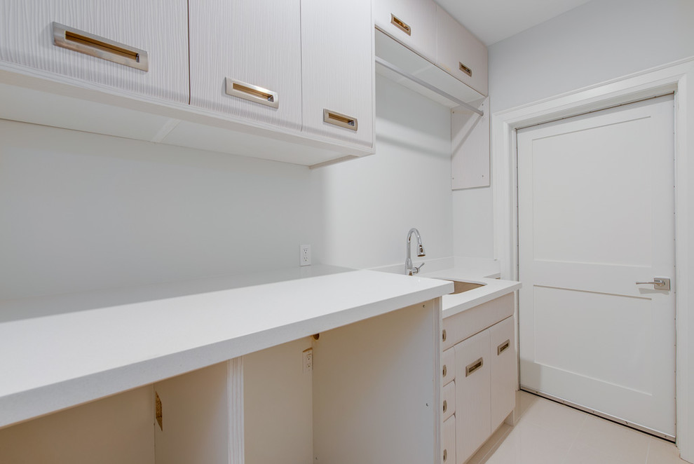 Design ideas for a small modern single-wall utility room in Toronto with an undermount sink, flat-panel cabinets, stainless steel cabinets, quartz benchtops, white walls, porcelain floors, a side-by-side washer and dryer, white floor and white benchtop.
