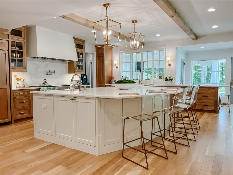 Town + Country Addition and Renovation - Our clients wanted a kitchen that could keep up with their family's pace. They love watching cooking competitions and wanted their kitchen to be the perfect spot for their kids to have cookie bake-offs. To make that possible, their kitchen needed to be wider, more capable, and more open than their current one, while still feeling connected to the family room. The wife wanted to be present with her family even while cooking, with a clear view of both the breakfast room and the family room wherever she stood. That sightline became the guiding principle for the entire space.

What came together is nothing short of a dream kitchen. The footprint was dramatically expanded as part of the addition, anchored by an oversized island with a bright quartz countertop that invites the whole family to pull up a stool and stay a while. Warm, natural wood cabinetry wraps the perimeter, grounding the space with richness and texture, while the white island keeps everything feeling bright and open. Exposed wood beams overhead carry warmth upward, and a pair of brass lantern pendants over the island add just the right amount of drama without competing with the natural light pouring in through the wall of windows in the breakfast room.

The butler's pantry, tucked just off the kitchen, adds the kind of storage and prep space that makes a busy household run smoothly, and gives the whole cooking experience a sense of ease and luxury that the family now wonders how they ever lived without. And with the family room and breakfast room always in view, separated only by open air, this kitchen doesn't just function beautifully. It draws everyone together exactly the way our clients always hoped it would.