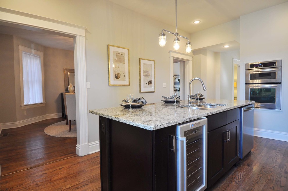 Inspiration for a mid-sized transitional galley medium tone wood floor enclosed kitchen remodel in St Louis with an undermount sink, shaker cabinets, granite countertops, white backsplash, subway tile backsplash, stainless steel appliances, an island and white cabinets