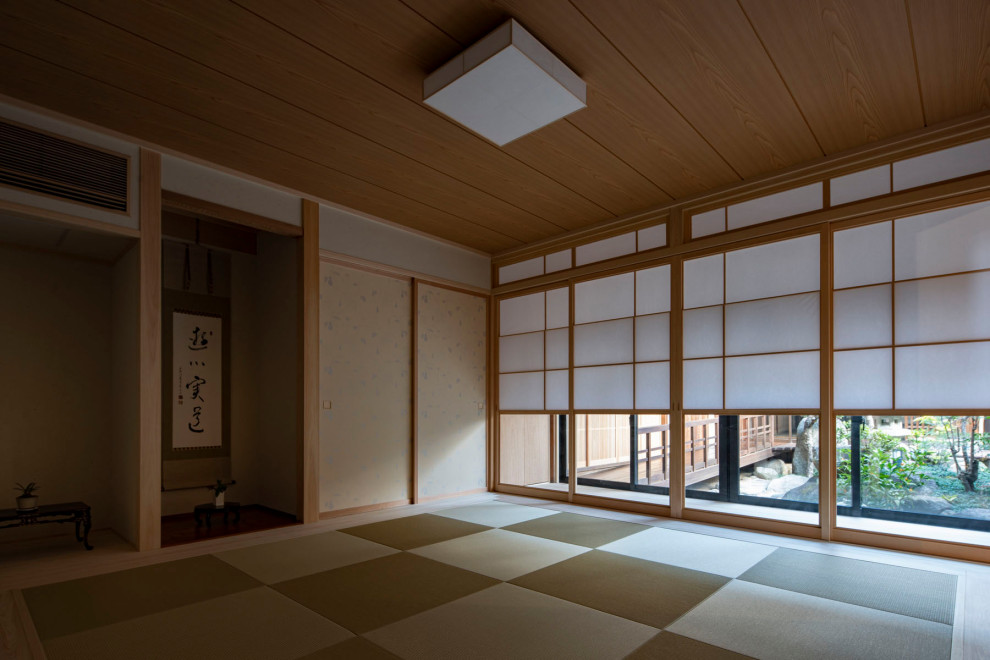 Cette image montre un grand salon fermé avec une salle de réception, un mur blanc, un sol de tatami, aucune cheminée, aucun téléviseur, un sol vert et un plafond en bois.