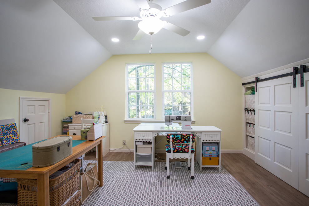 Design ideas for a large modern craft room in Houston with yellow walls, laminate floors, a freestanding desk, brown floor and vaulted.