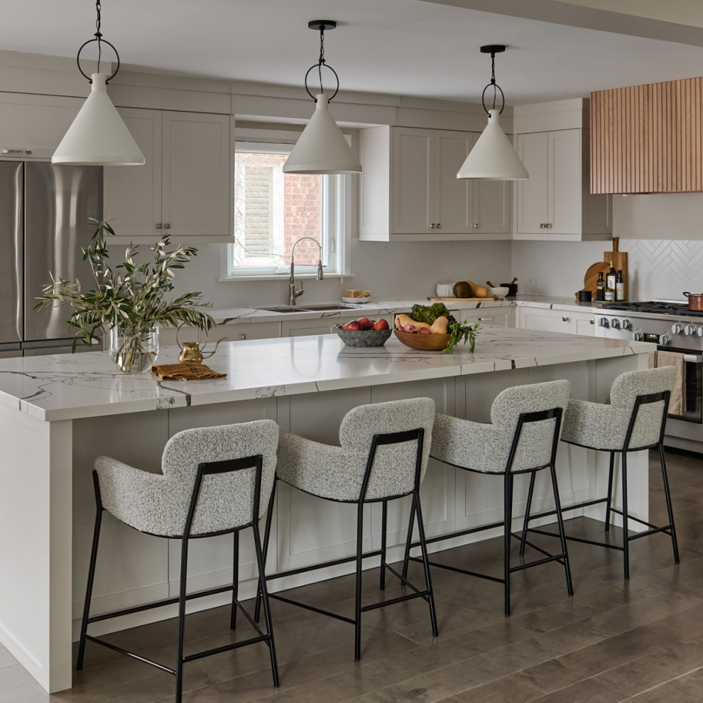 Photo of a mid-sized transitional l-shaped open plan kitchen in Toronto with a triple-bowl sink, shaker cabinets, beige cabinets, quartz benchtops, white splashback, porcelain splashback, stainless steel appliances, dark hardwood floors, with island, brown floor and white benchtop.