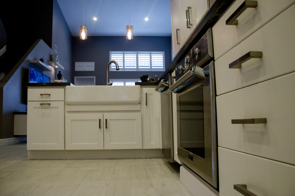 Example of a small transitional u-shaped porcelain tile kitchen design in Miami with a farmhouse sink, shaker cabinets, white cabinets, quartz countertops, gray backsplash, stone tile backsplash, stainless steel appliances and no island