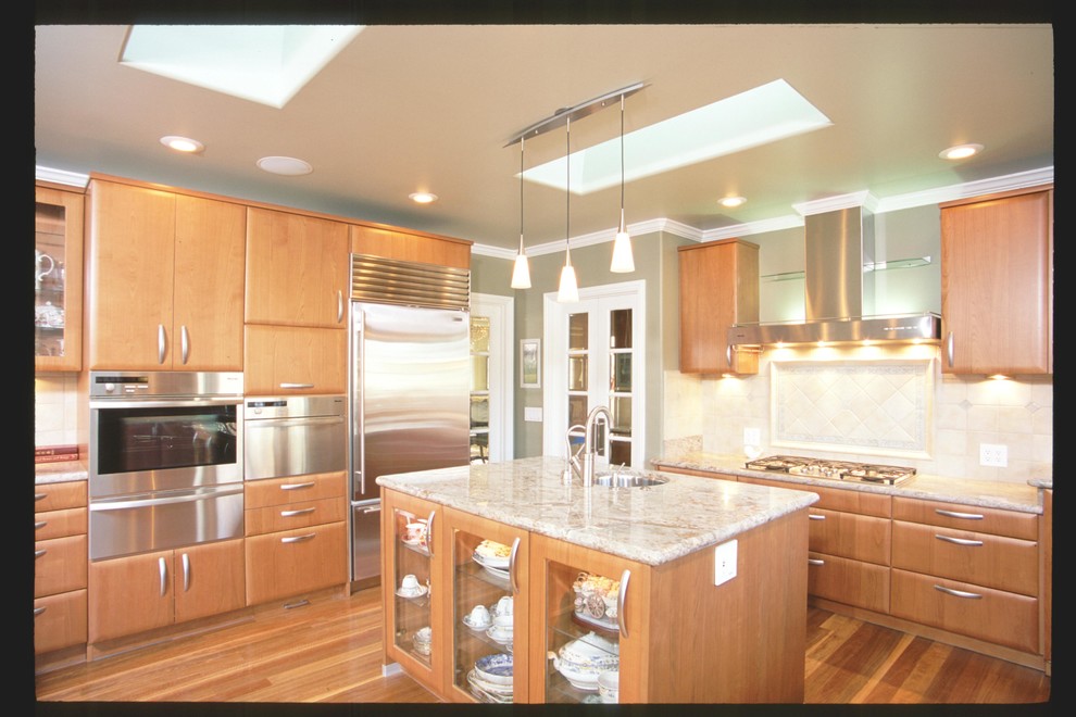 This is an example of a transitional separate kitchen in San Francisco with an undermount sink, flat-panel cabinets, medium wood cabinets, granite benchtops, beige splashback, stone slab splashback, stainless steel appliances, medium hardwood floors and with island.