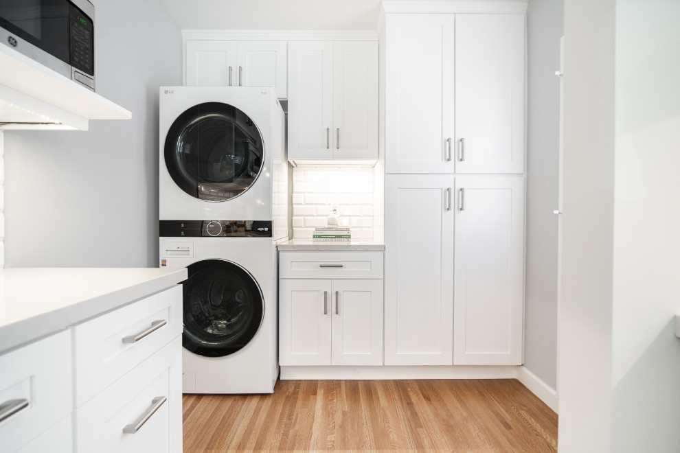 Inspiration for a large country u-shaped laundry room in Los Angeles with white cabinets, marble benchtops, white splashback, subway tile splashback, painted wood floors, brown floor and grey benchtop.
