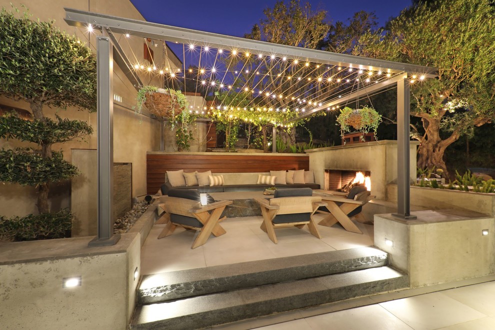 Large contemporary side yard patio in Orange County with with fireplace, concrete slab and a pergola.